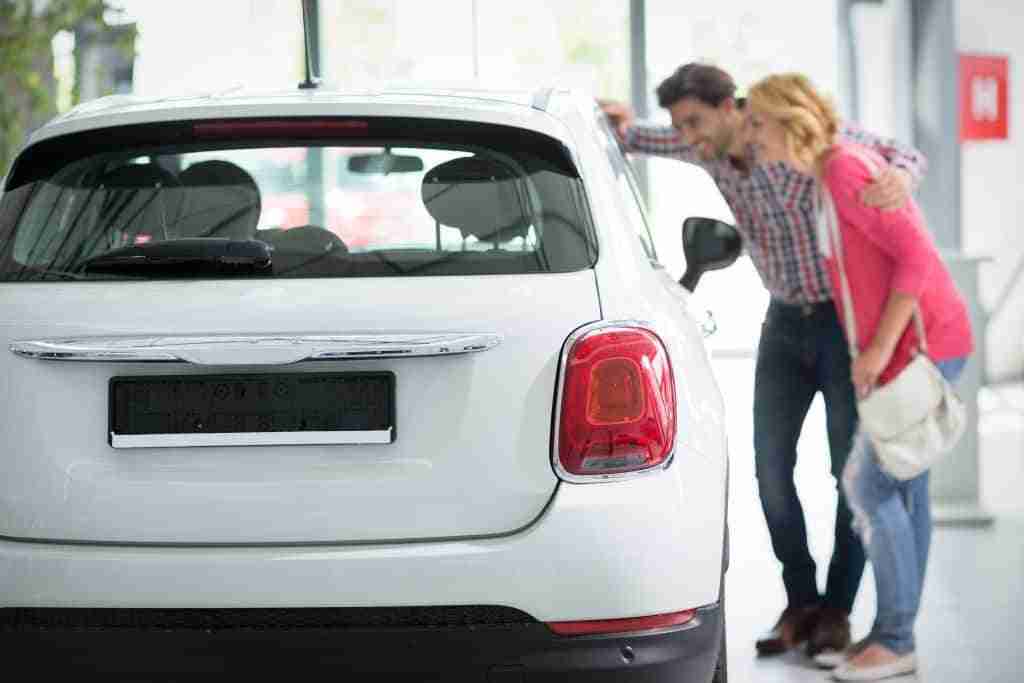 How Can Your Business Generate More Car Loan Leads? 1 Young couple looking at the inside of a new car at a dealership