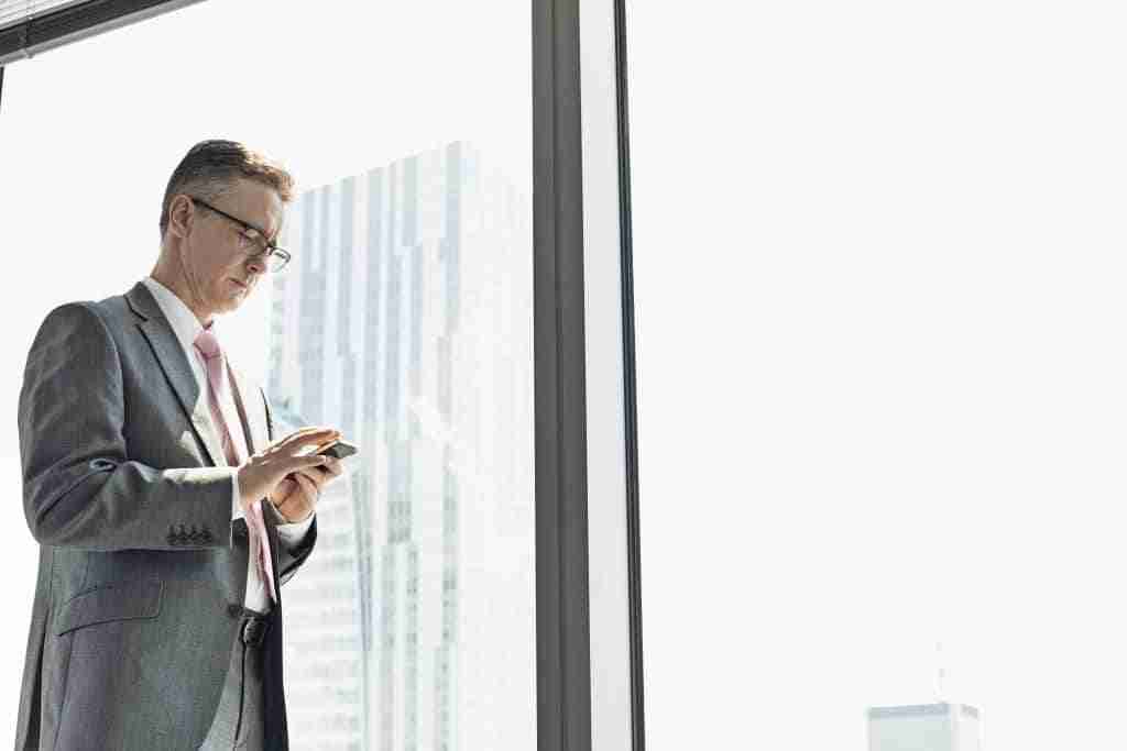 Business man standing at the window and texting